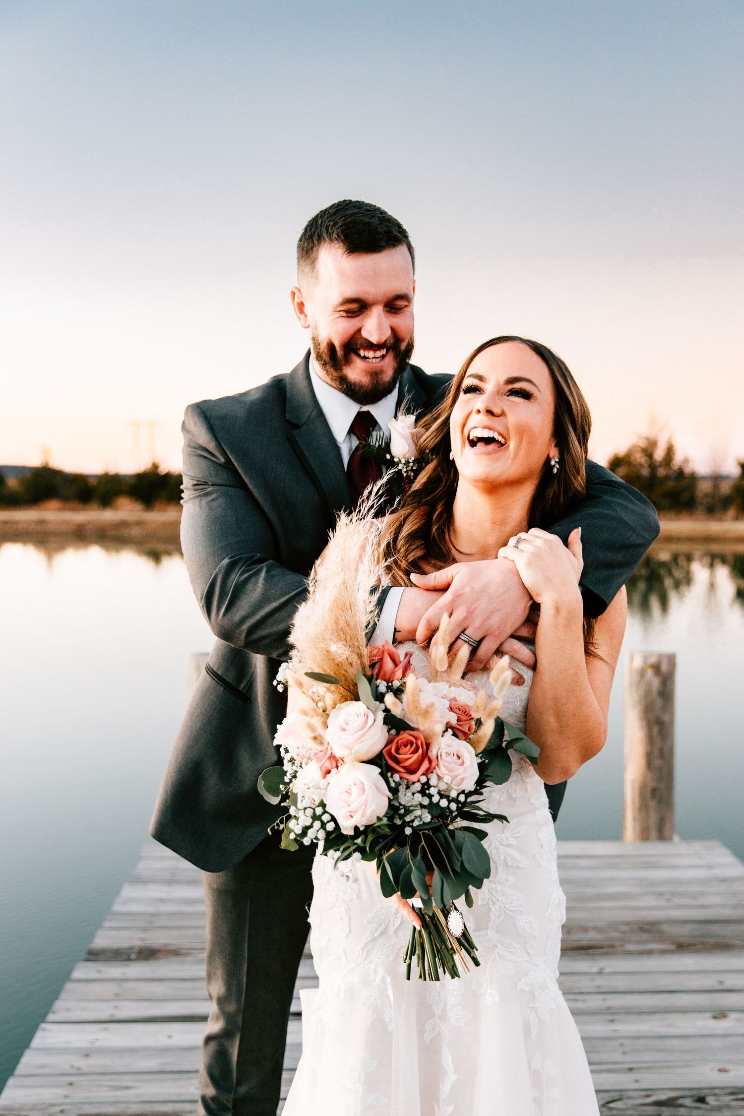 A couple pose for their wedding portraits on a dock just outside their wedding venue at Bridle Creek in Sperry, Oklahoma.