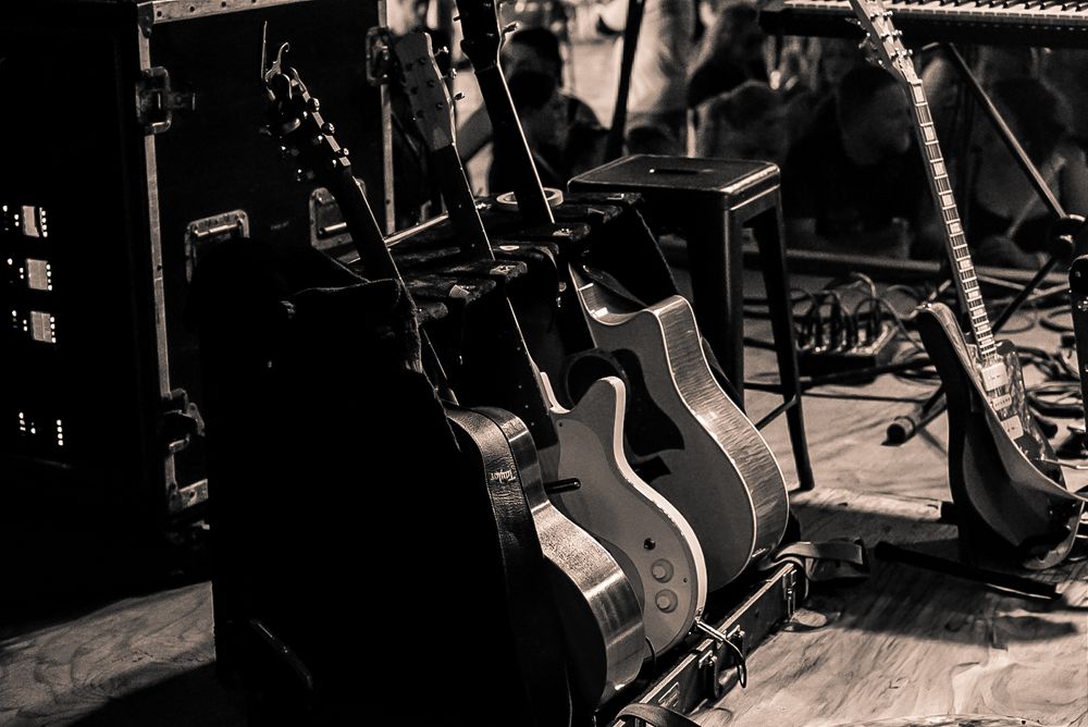 Several acoustic guitars stand propped backstage during a concert setup.