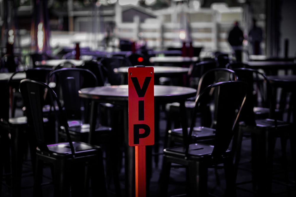 Empty restaurant interior with red VIP sign standing among dark wooden chairs.