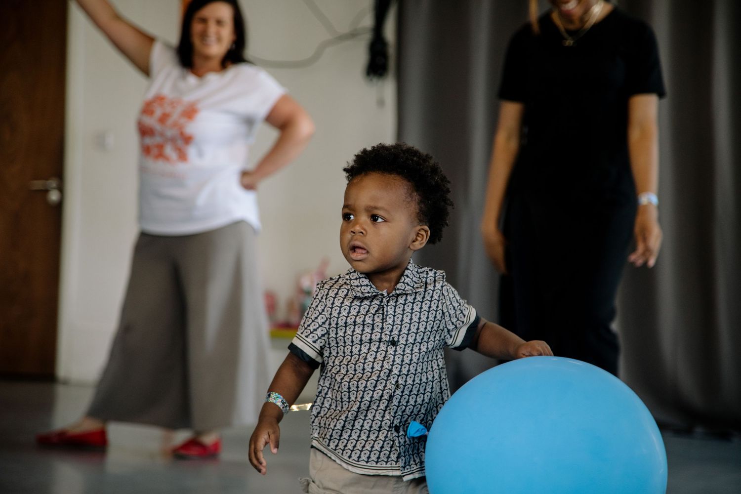 Child playing with blue balloon during indoor activity session.