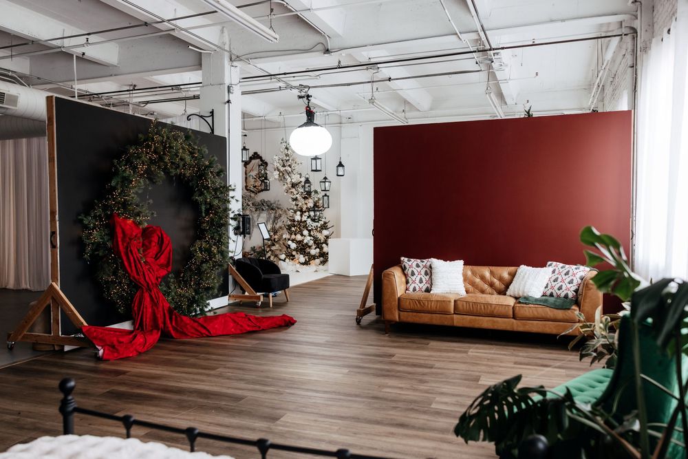 Modern living room decorated for Christmas with red and green accents, a wooden bench, and holiday decorations.