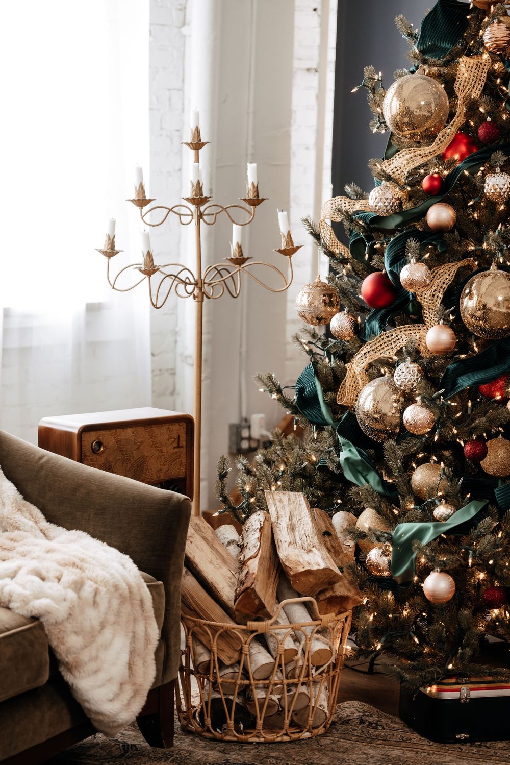 Cozy Christmas scene with decorated tree, plush blanket, and elegant candelabra in a warm living room setting.