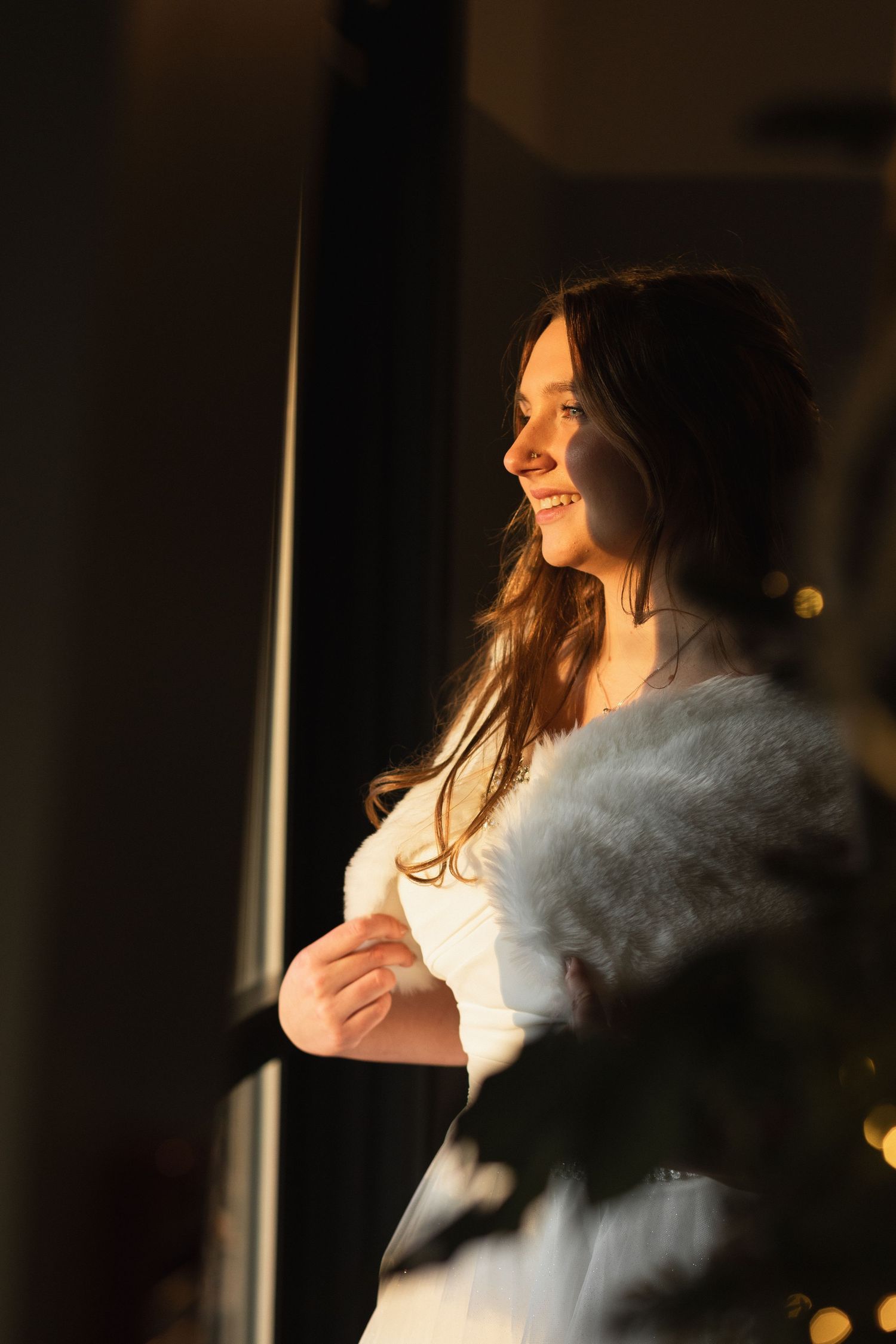 A woman in a white top stands in dramatic side lighting as her hair flows in the breeze.