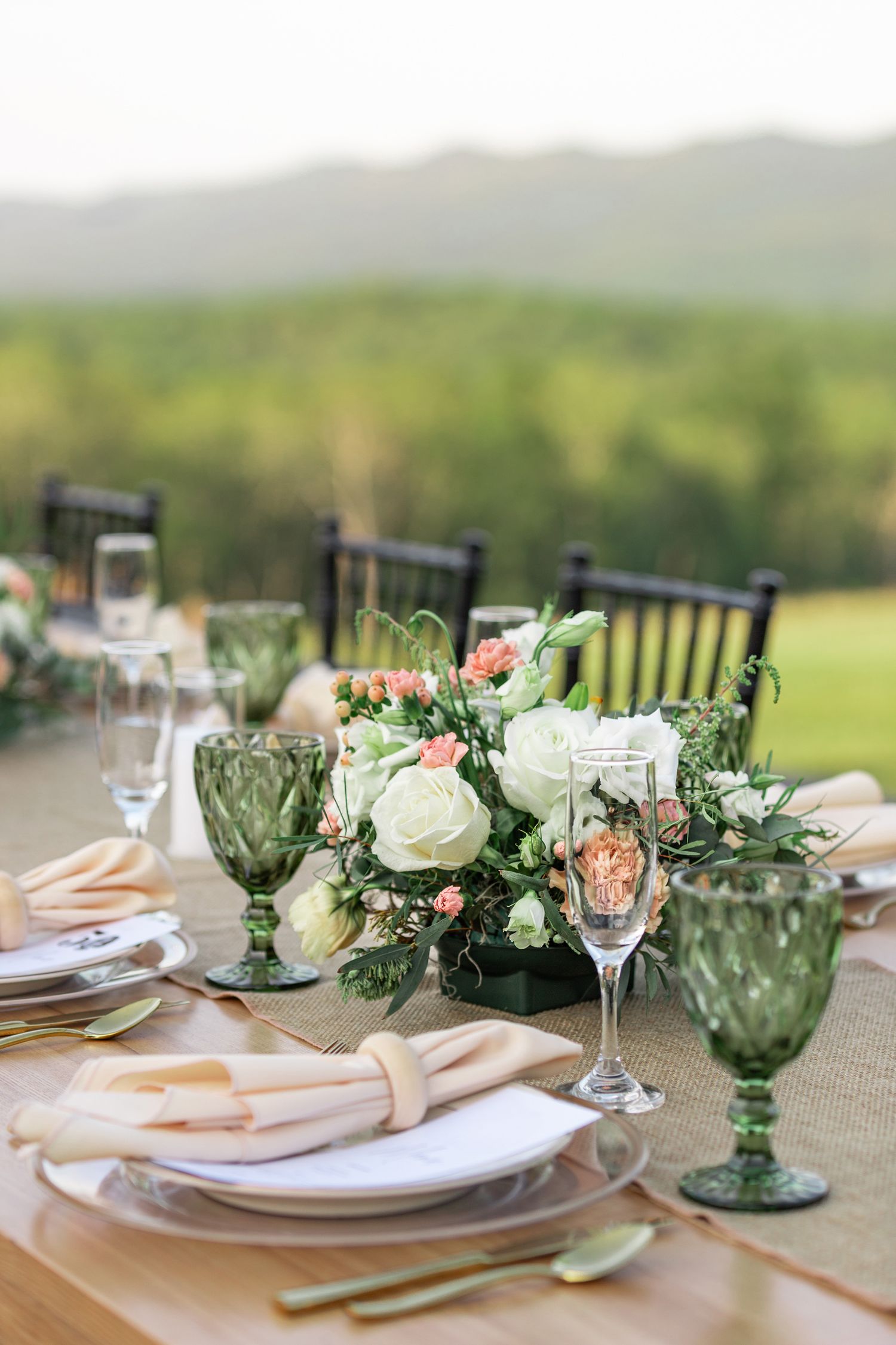 Elegant table settings with green glassware and white roses arranged for outdoor wedding reception in the mountains of Shenandoah Valley