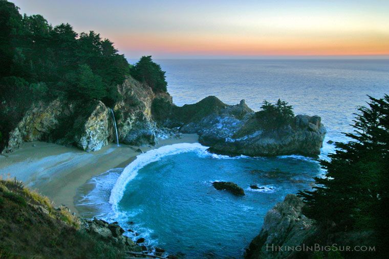 Sunset over McWay Falls cascading onto a secluded beach cove along Big Sur coastline, California.