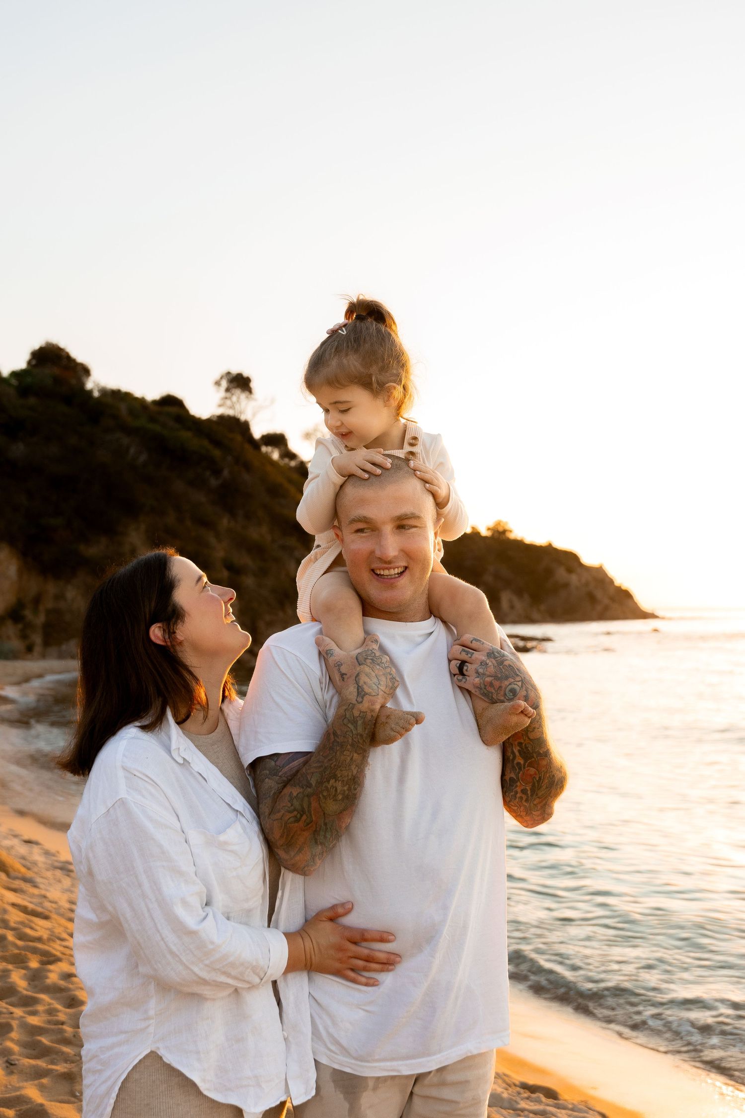 Family enjoying tender moments together on a beach at sunset.