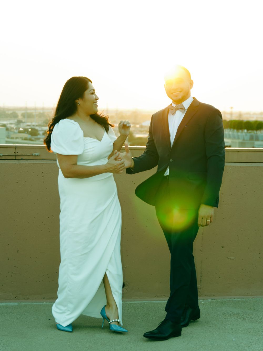 A couple sharing a dance on a rooftop terrace during sunset, with warm golden lighting.