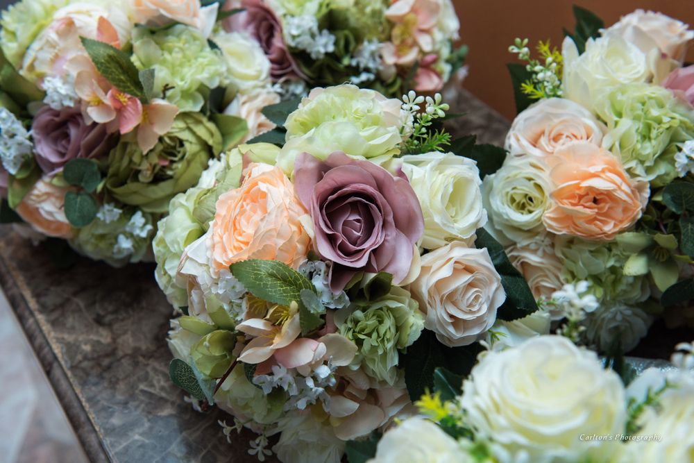 Beautiful wedding bouquets featuring peach, purple and white roses with green accents arranged on a wooden surface.