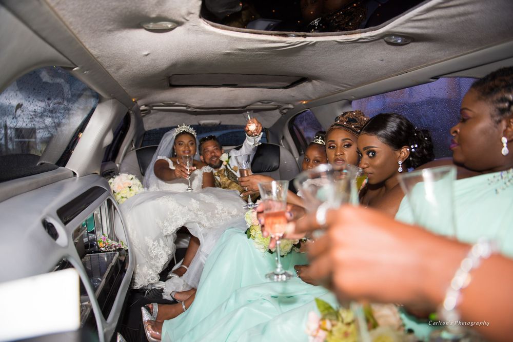 Wedding party members celebrate together inside a vehicle.