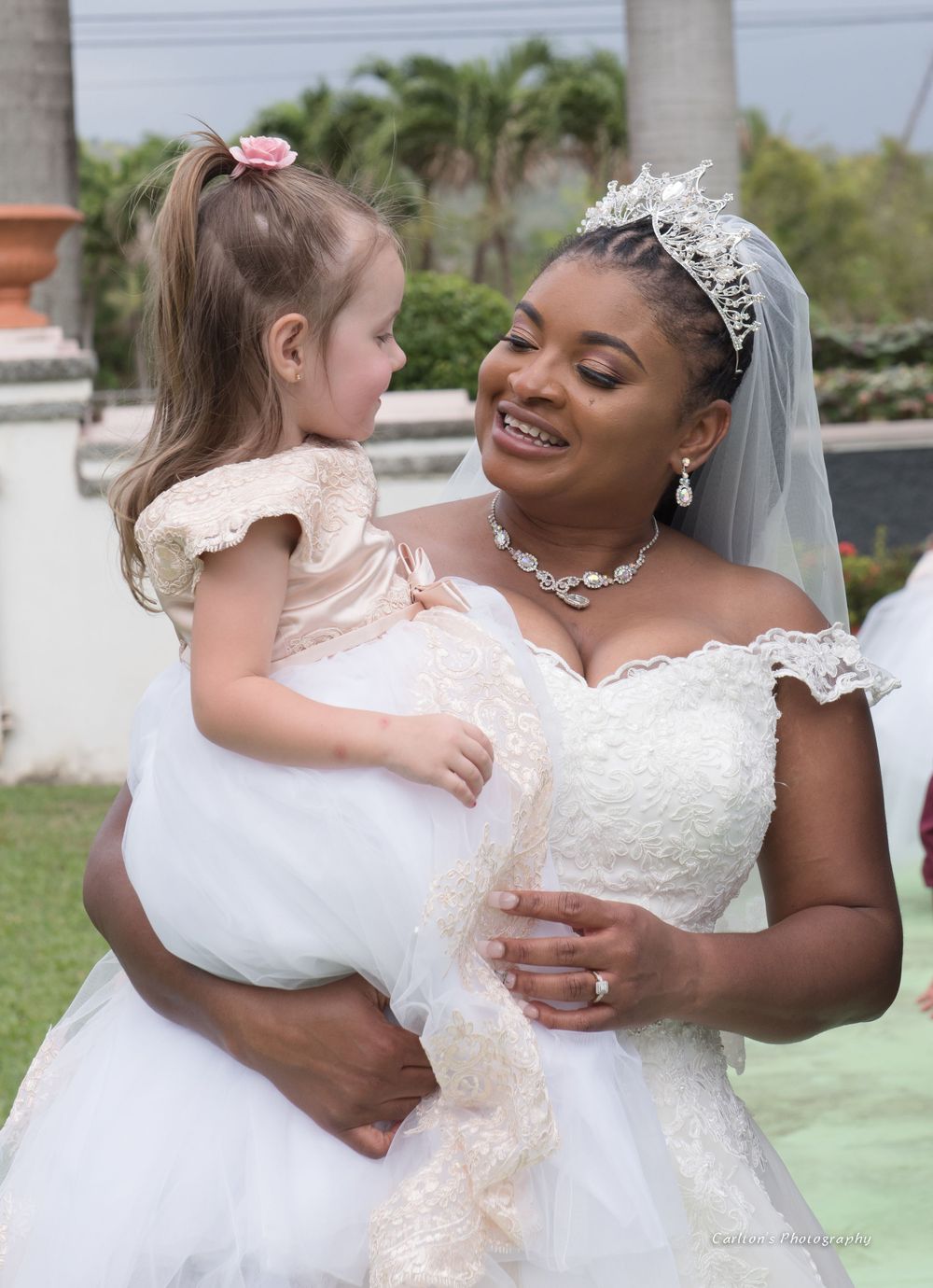 A tender moment between a bride in a white gown and small flower girl in pink.