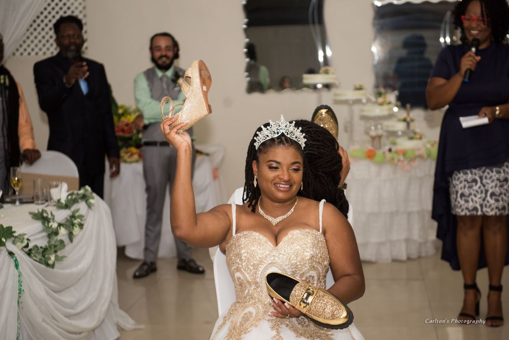 A bride in a white dress holds up a shoe during wedding reception celebrations.