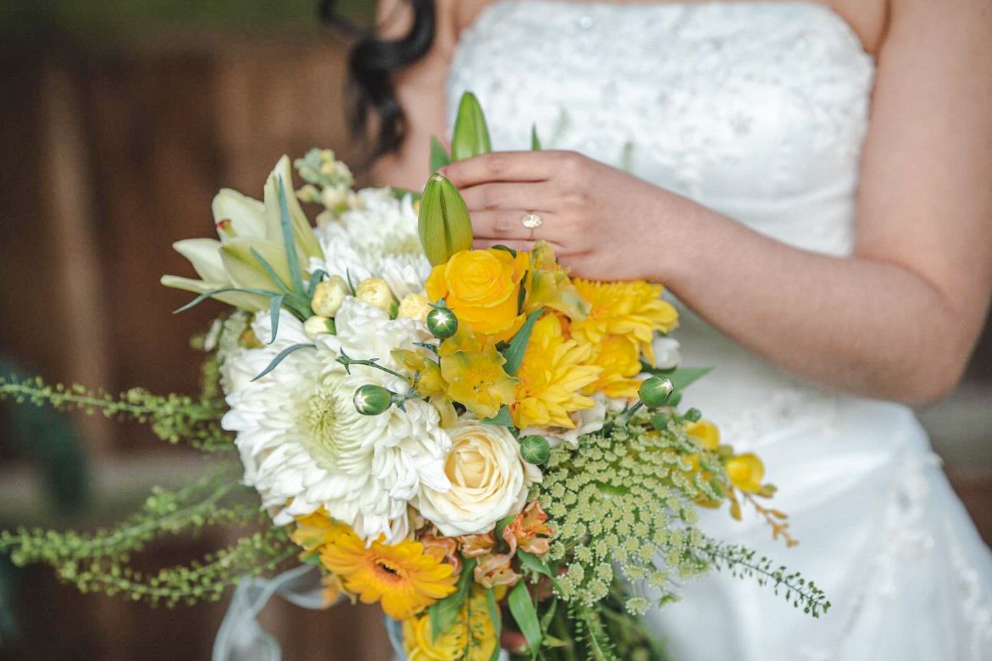 Close-up of bridal bouquet featuring sunny yellow flowers and white blooms.