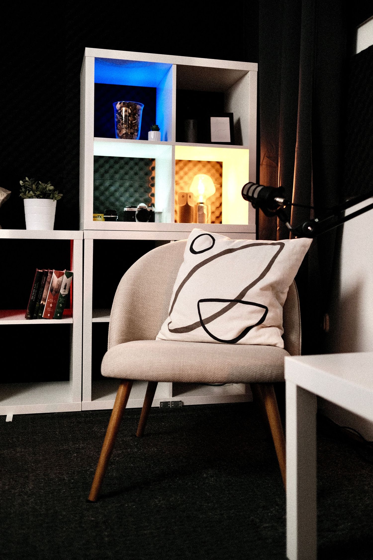 Modern podcast studio corner with designer chair and cubby storage unit.