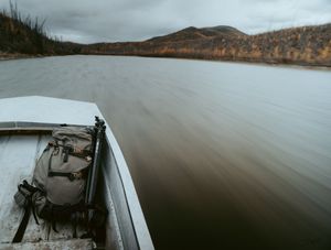 Panoramic view of a misty lake surrounded by mountains under cloudy skies.