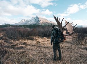 Panoramic sequence of a hunter tracking through rugged mountain terrain during a hunting expedition.