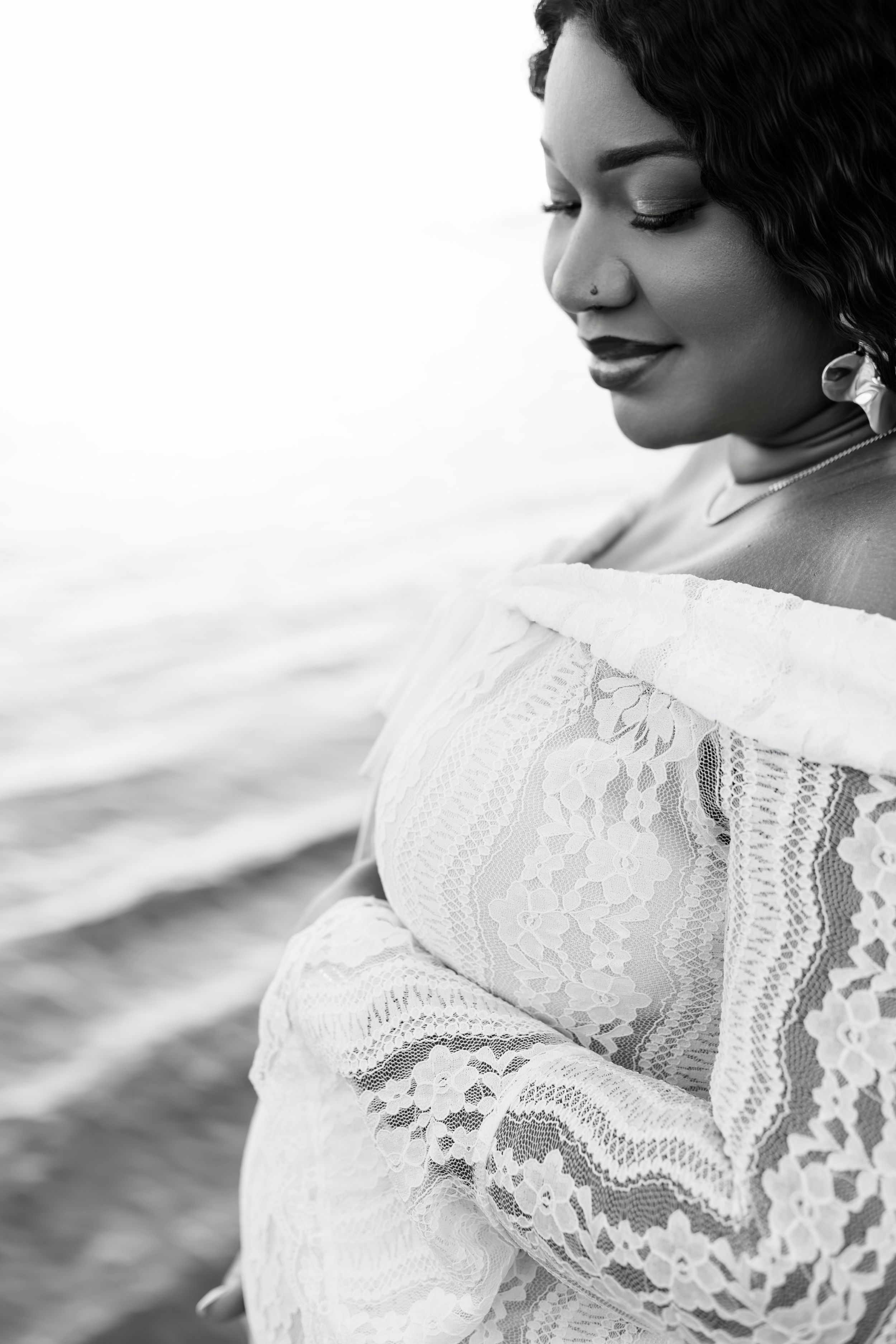 A black and white close-up photograph showing delicate white lace details against a light background.