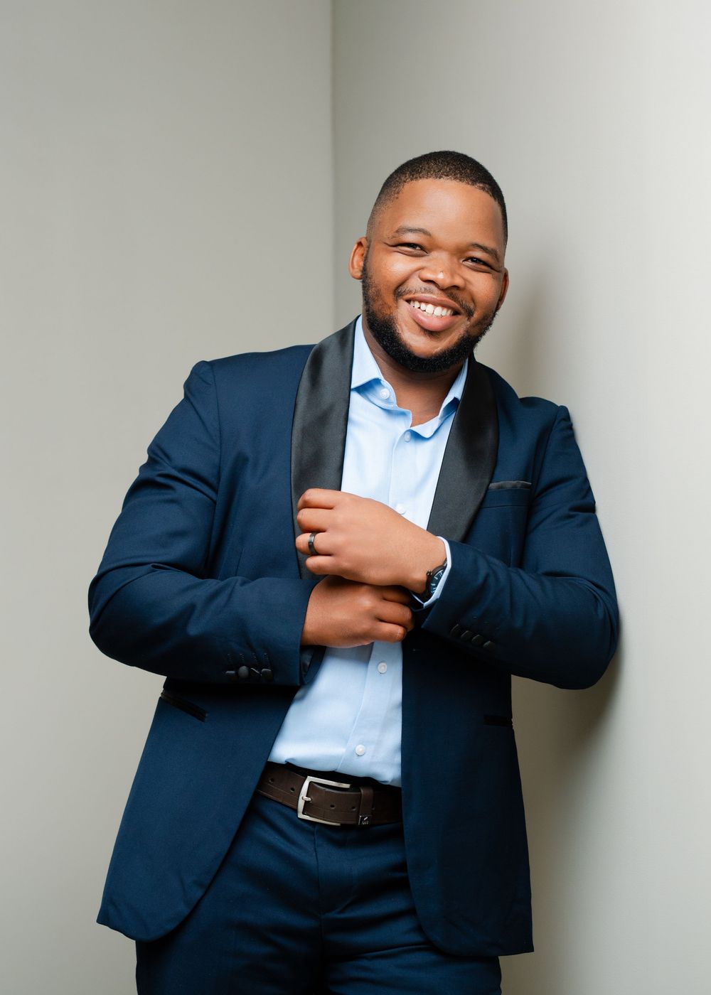 Professional wearing a navy suit and light blue shirt smiles warmly in a series of expressive business portraits.