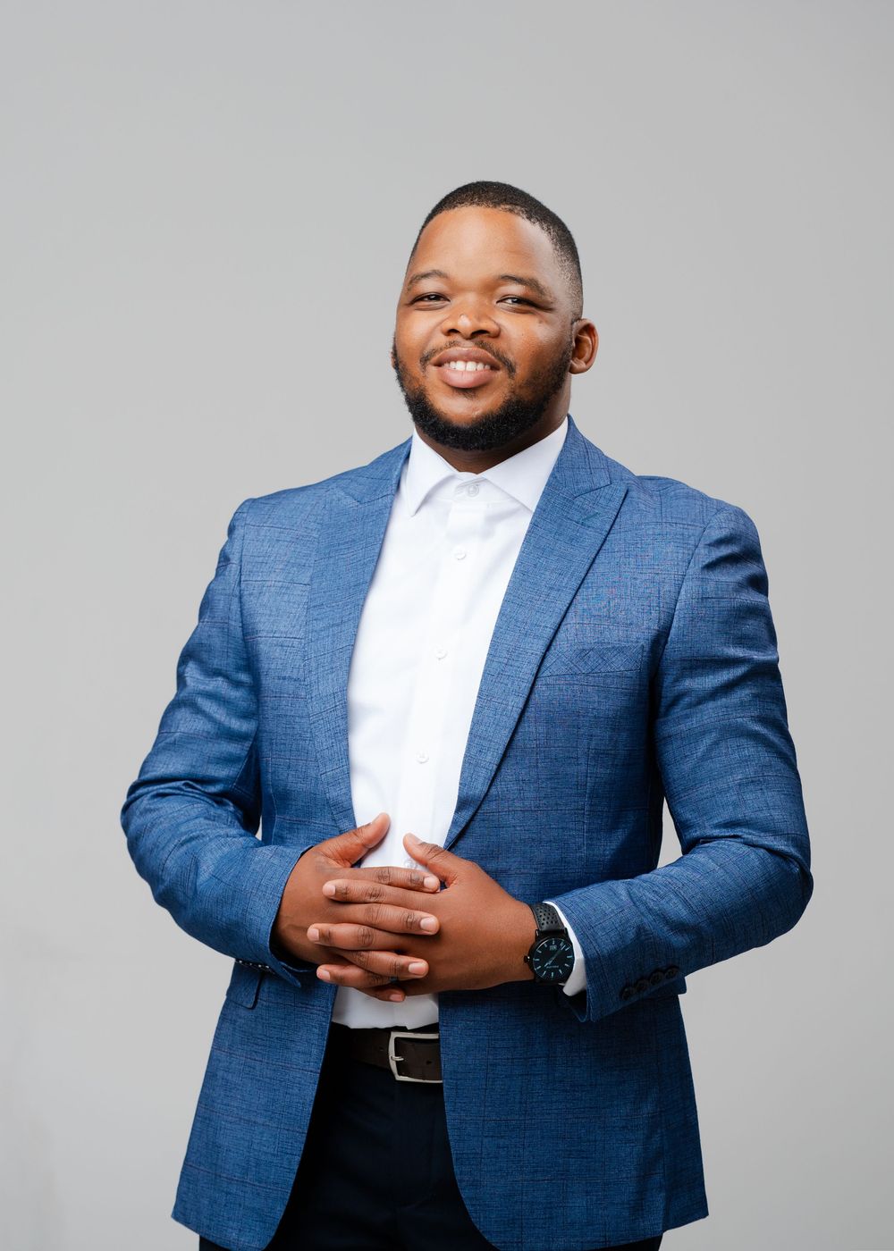 Professional portrait of someone wearing a blue suit jacket and white dress shirt against a gray background.