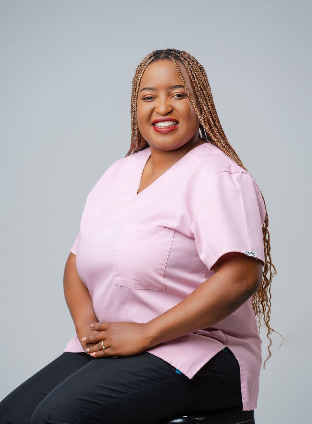 A healthcare professional in pink scrubs poses confidently against a gray background in a series of portraits.