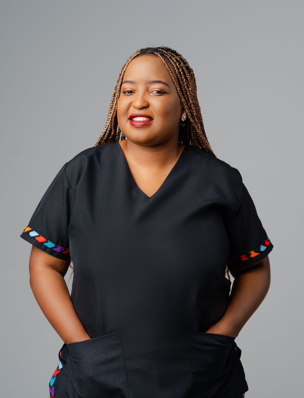 Professional portrait of someone wearing a black v-neck top with colorful trim detail against a gray background.