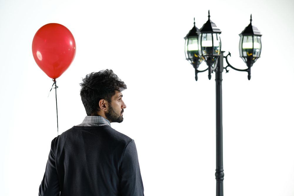 Minimalist scene with red balloon, vintage street lamp, and white backdrop.