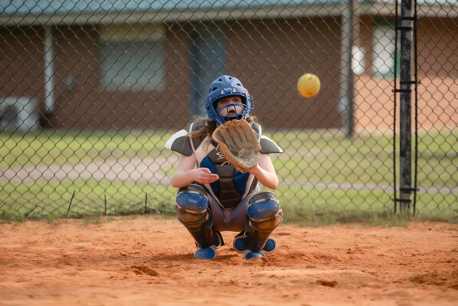 Baseball player sliding into base during game on dirt infield.