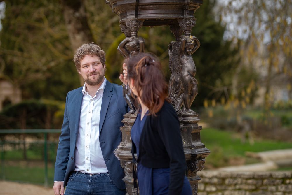 A couple poses together in a garden setting during an outdoor photo session at dusk.