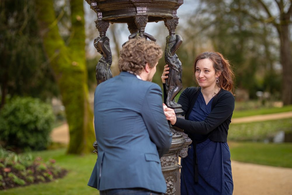 Couple in blue outfits sharing a romantic moment outdoors in a park setting.