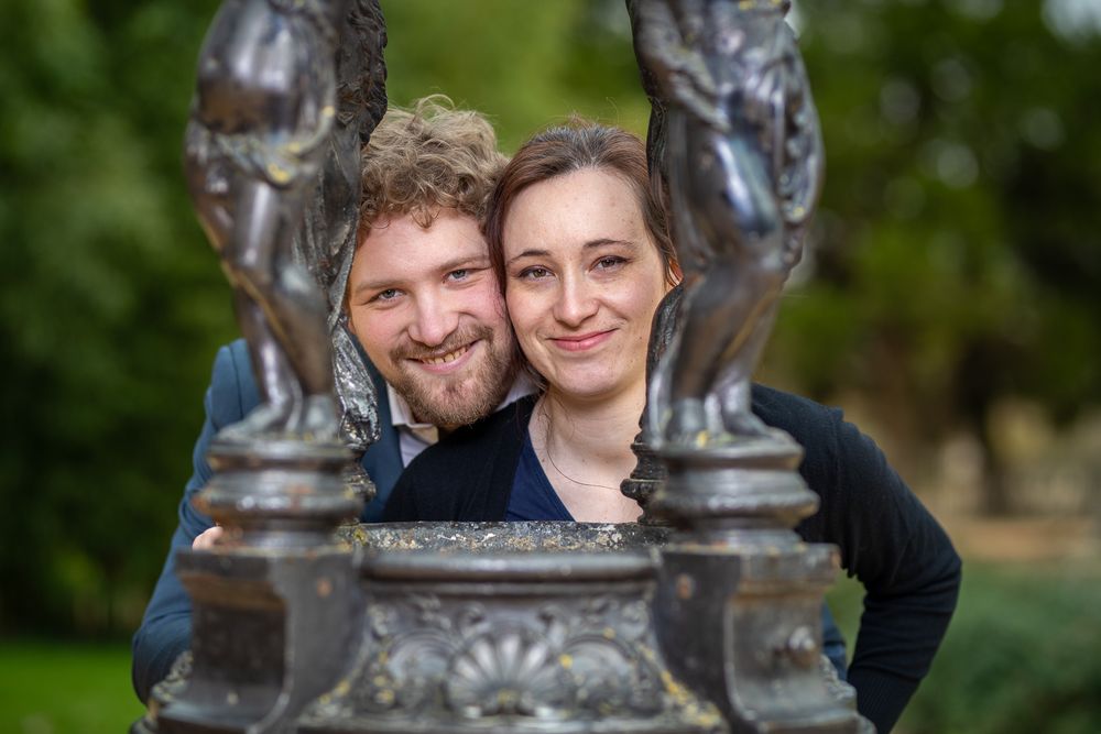 People laugh joyfully together during an outdoor photoshoot in a natural setting.
