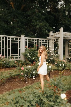 High school senior walking through garden of roses on a summer evening.