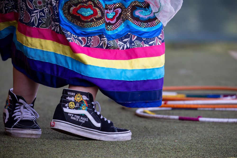 Sneakers and colorful striped traditional clothing detail against green surface.