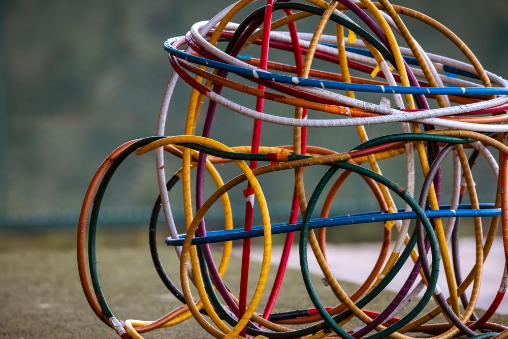 Collection of multicolored plastic hula hoops stacked together against a dark background.