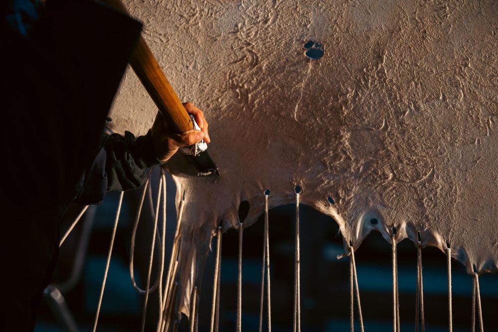 Collection of metal tools hanging on a textured wall with dramatic lighting.