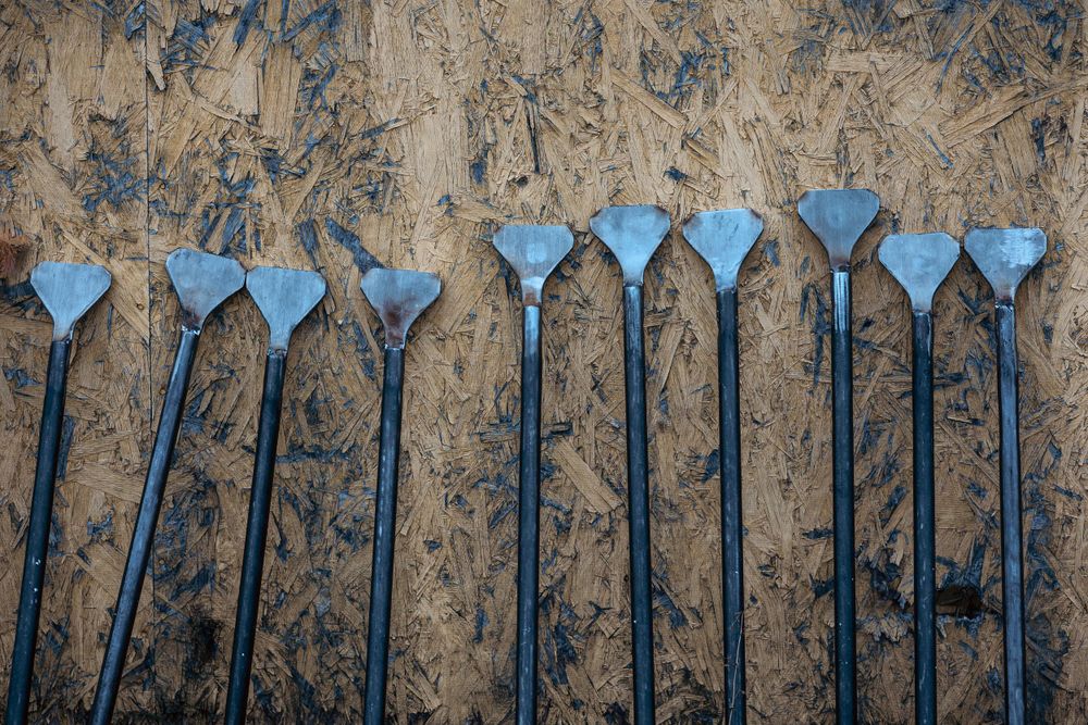 Row of identical blue metal tools arranged against weathered wooden background.