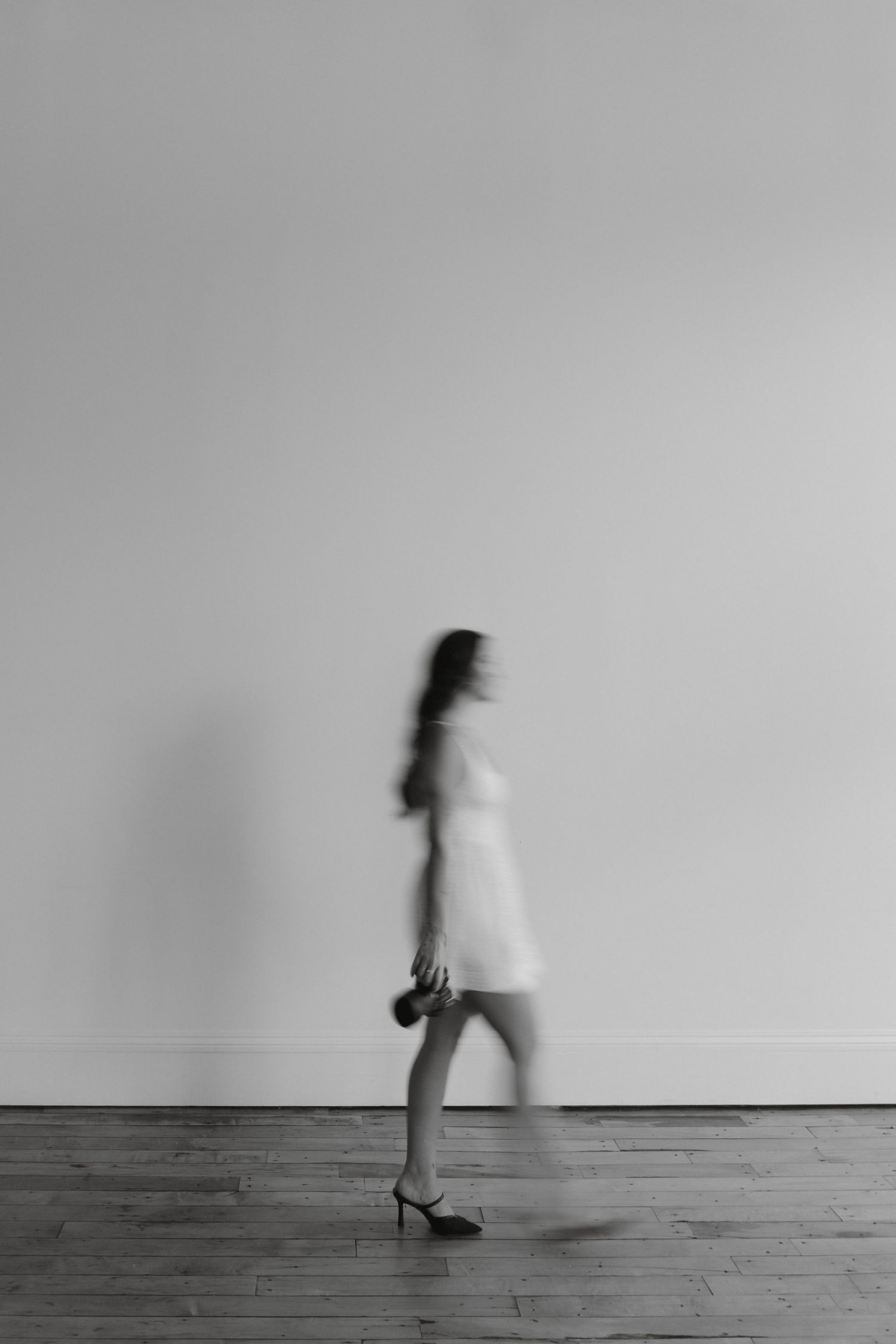 A black and white motion shot of two people passing between classical columns.