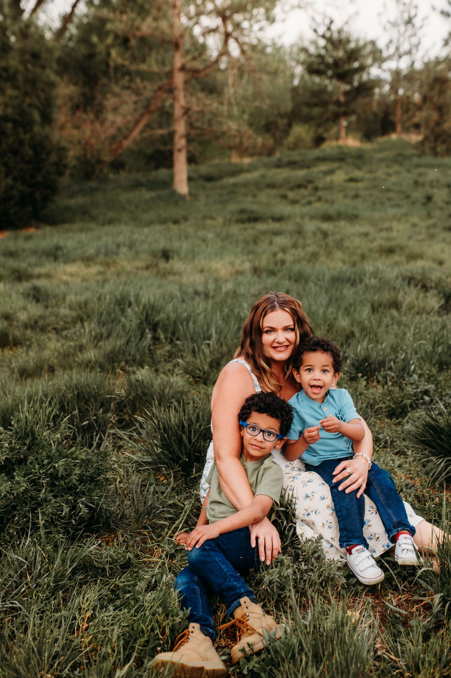 family sitting in lush green grass, smiling and embracing.