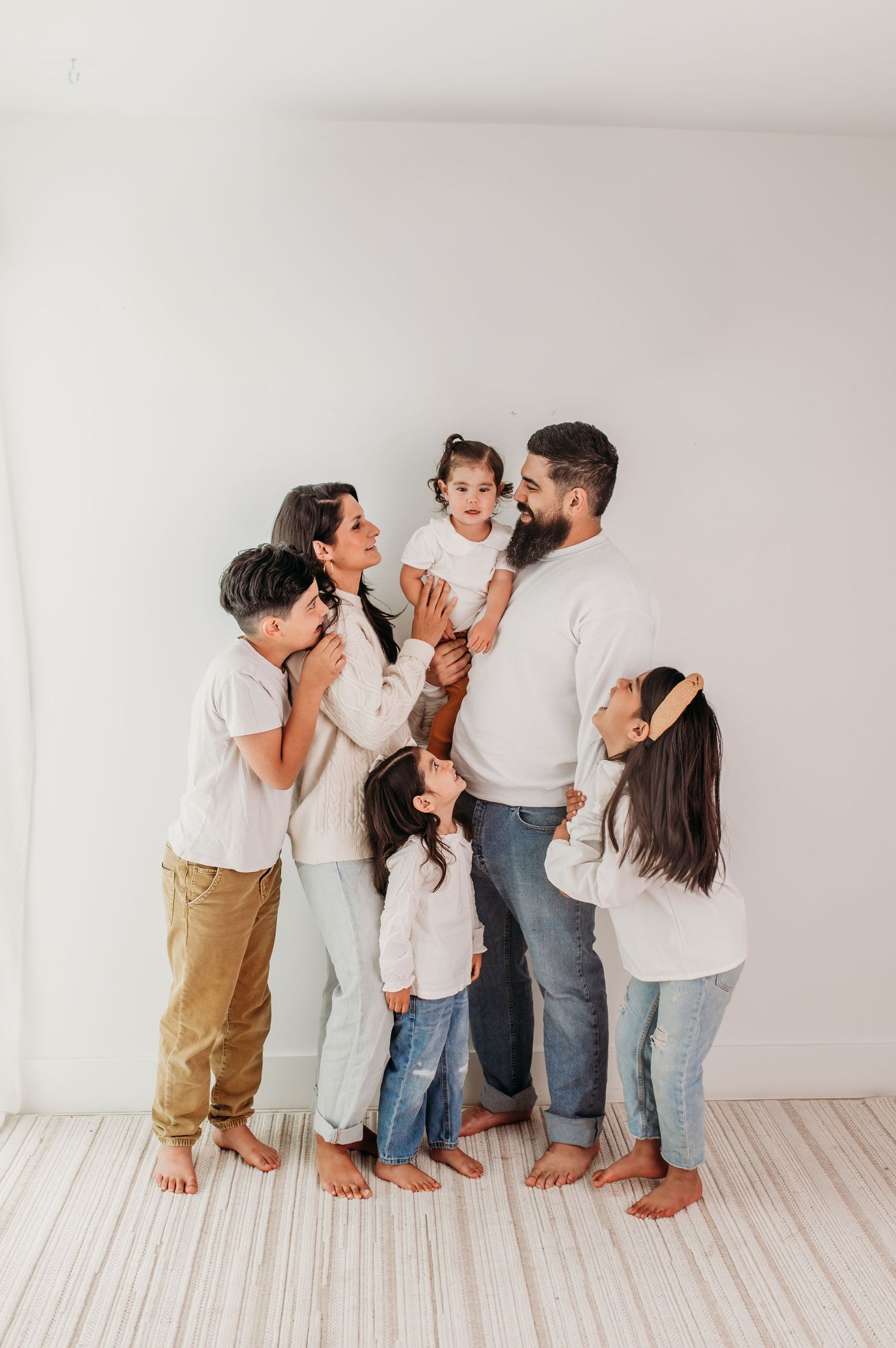 Studio portrait of a family of six laughing and playing in studio.