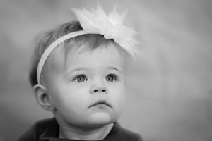 Black and white portrait of baby wearing white flower headband.
