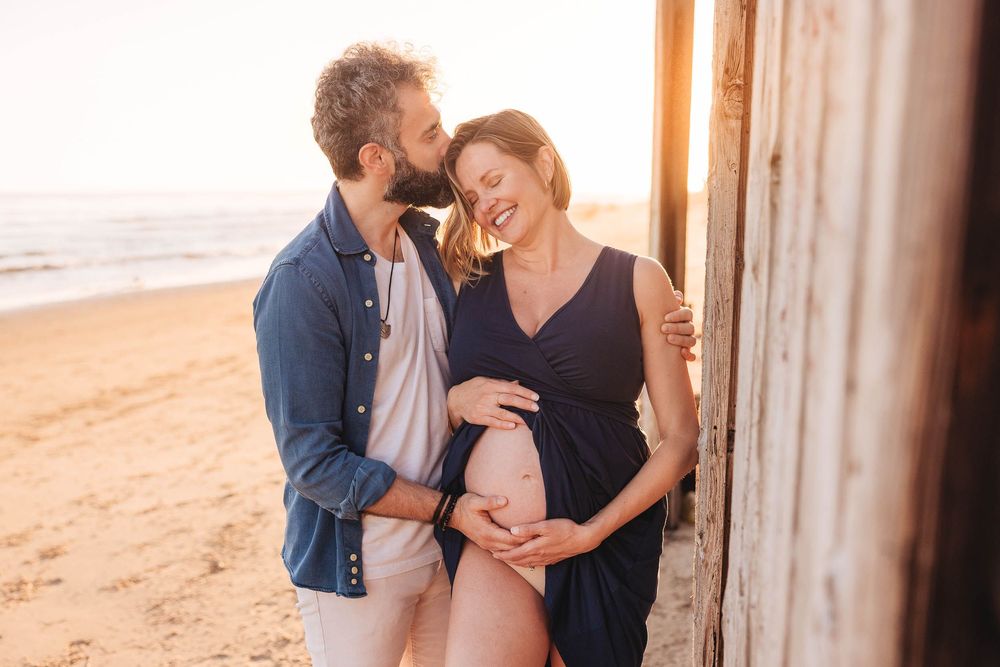 Tender moments captured between a couple during a golden hour beach photoshoot.