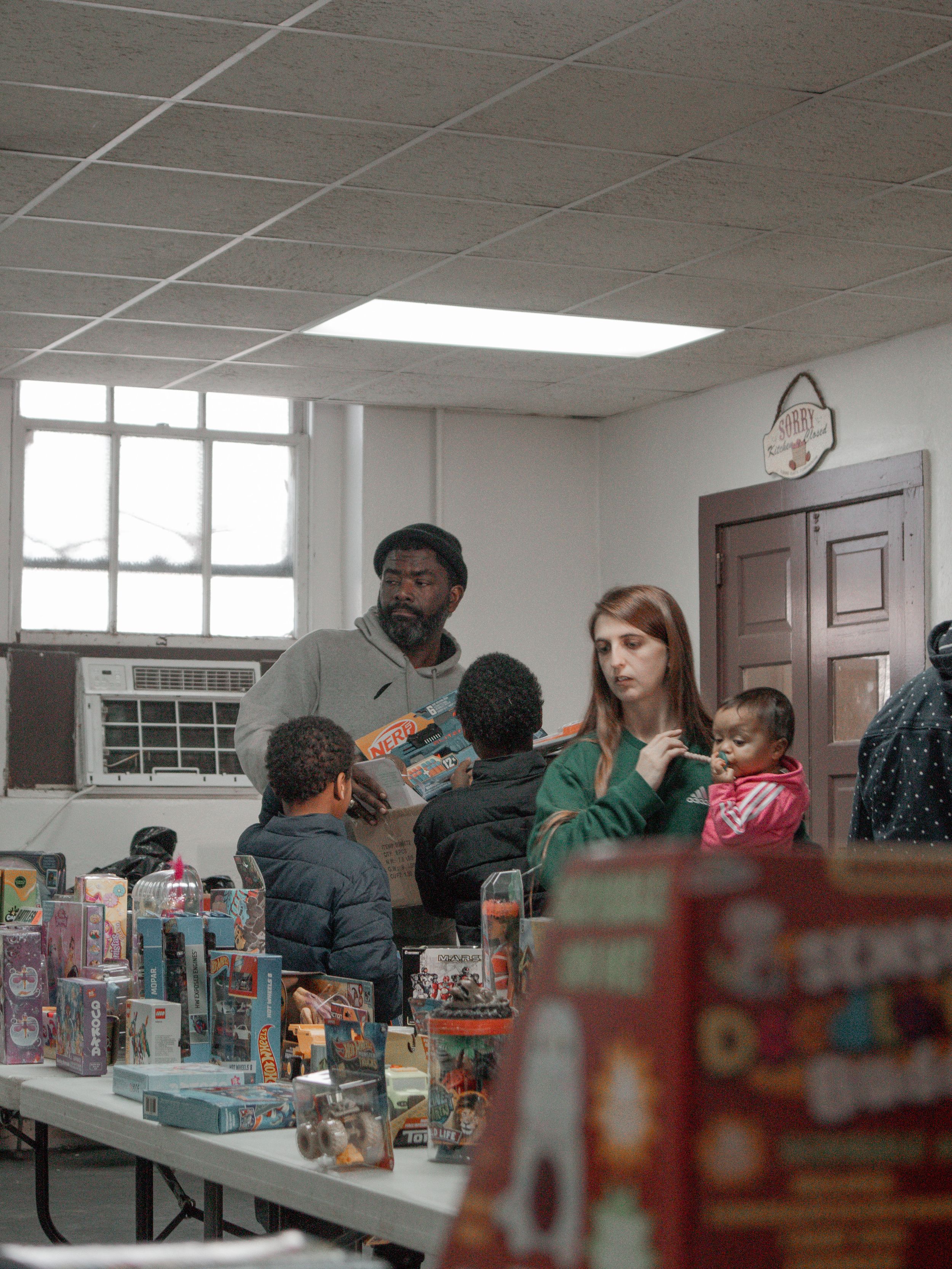 People gathered around a table displaying various toys and games during a community event.