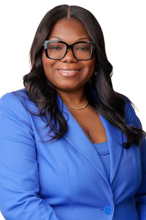 Professional woman in blue blazer and glasses smiling confidently against white background for business portrait.
