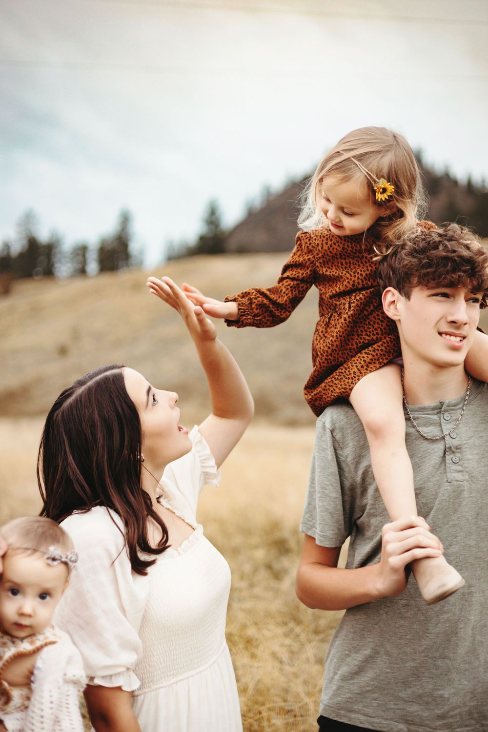 Family enjoying a playful moment together outdoors in a mountain meadow during golden hour in autumn.