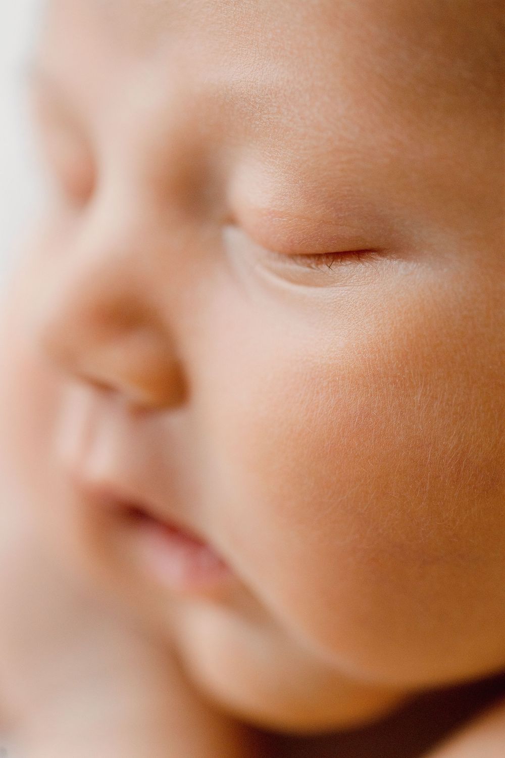 Close-up of a peaceful sleeping newborn baby's face with soft skin and delicate features.