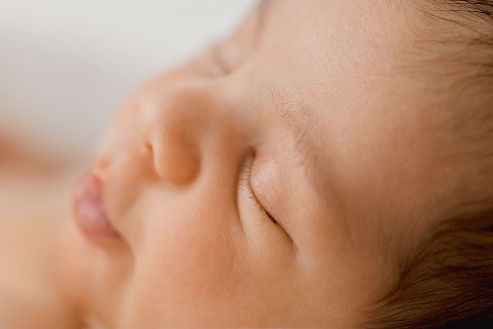 Close-up of a sleeping newborn baby with soft skin and peaceful expression.