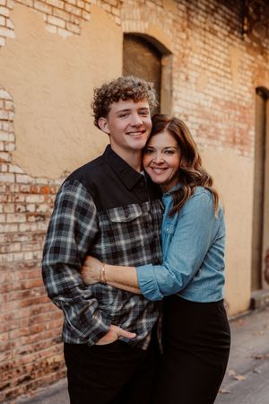 Mother and son sharing laughs against rustic brick wall background in Olathe, Kansas