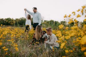 Family enjoying time together in a field of Kansas yellow wildflowers during golden hour.