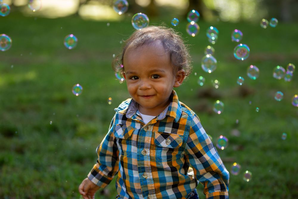 First birthday portrait outdoors with bubbles in the background.