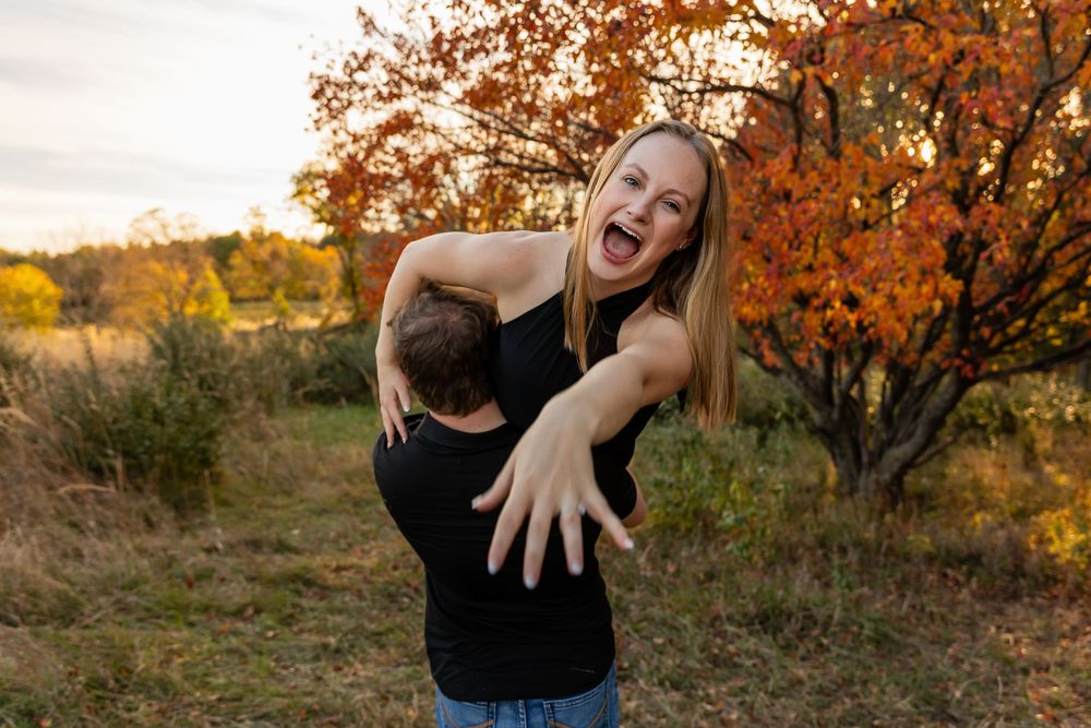 A joyful moment captured as a couple plays and laughs in a fall setting.