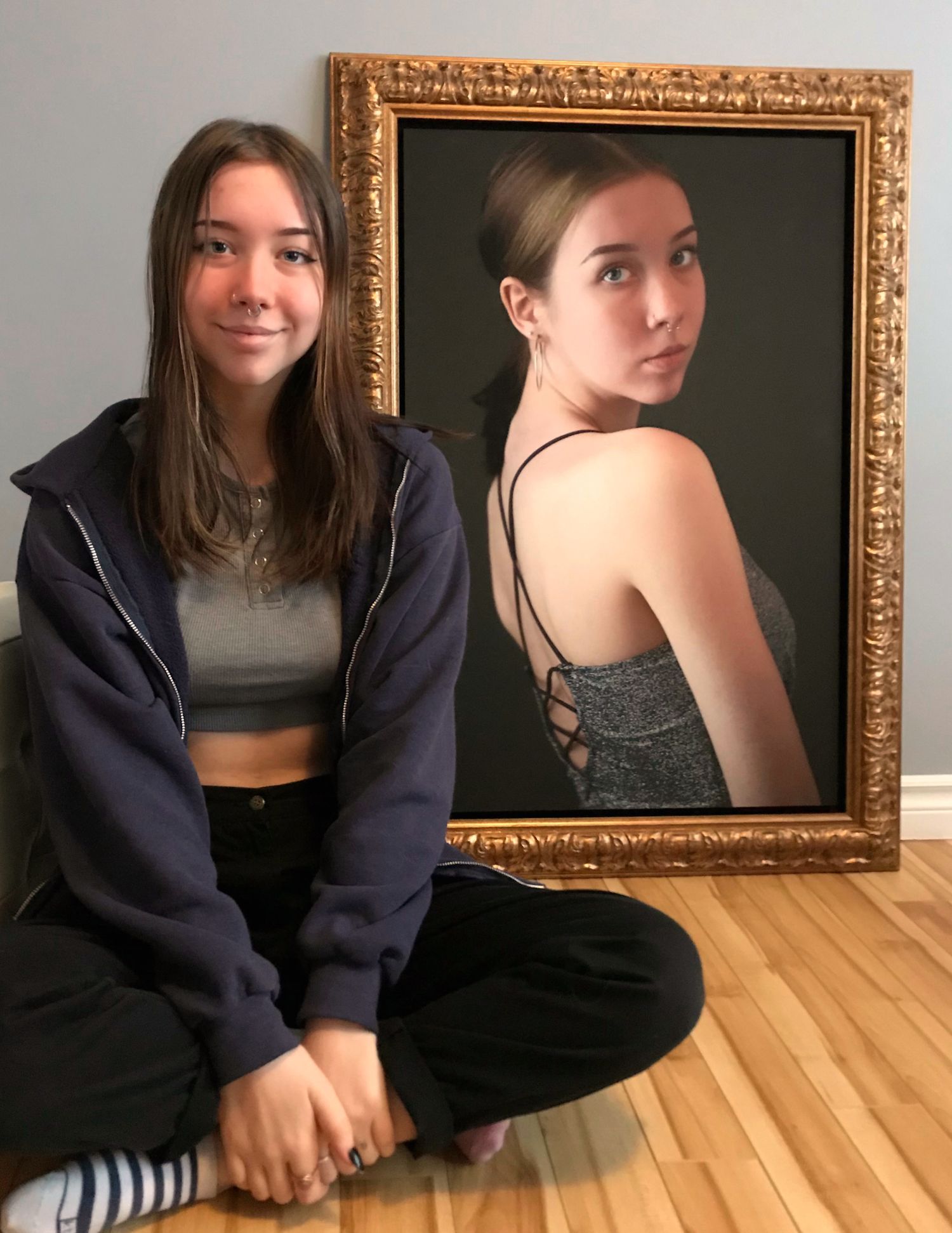 Cliché d'une jeune cliente à côté de l'encadrement  d'un de ses portraits.  Selfie of a young client next to one of her framed portraits.