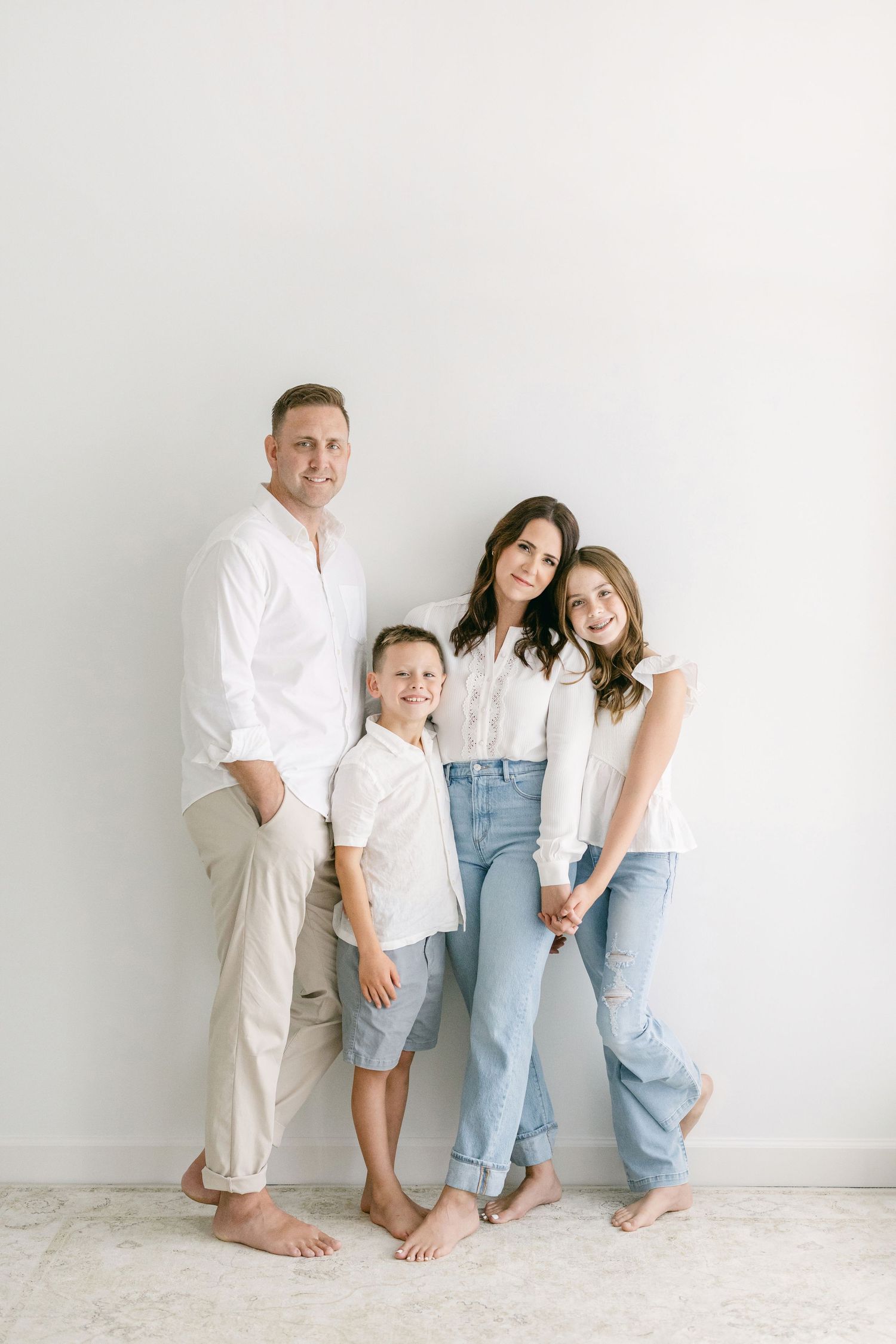A playful family portrait with children being silly on a white bed.